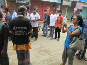 While the local inhabitants of Phulbari were busy marching on the streets of their own small town many 'outsiders' were taking notes and photos of them. Prominent journalist and feminist poet, short story writer Shameema Binte Rahman is photographing one marchers in my shot while I am busy capturing the slogan on the t-shirt of the marcher. The slogan: "We don't want the coal mine by destroying permanent (read non-renewable) resources. Inhabitants of Phulbari"  